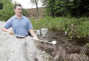 RJ Beck with a dipper for monitoring mosquito larvae